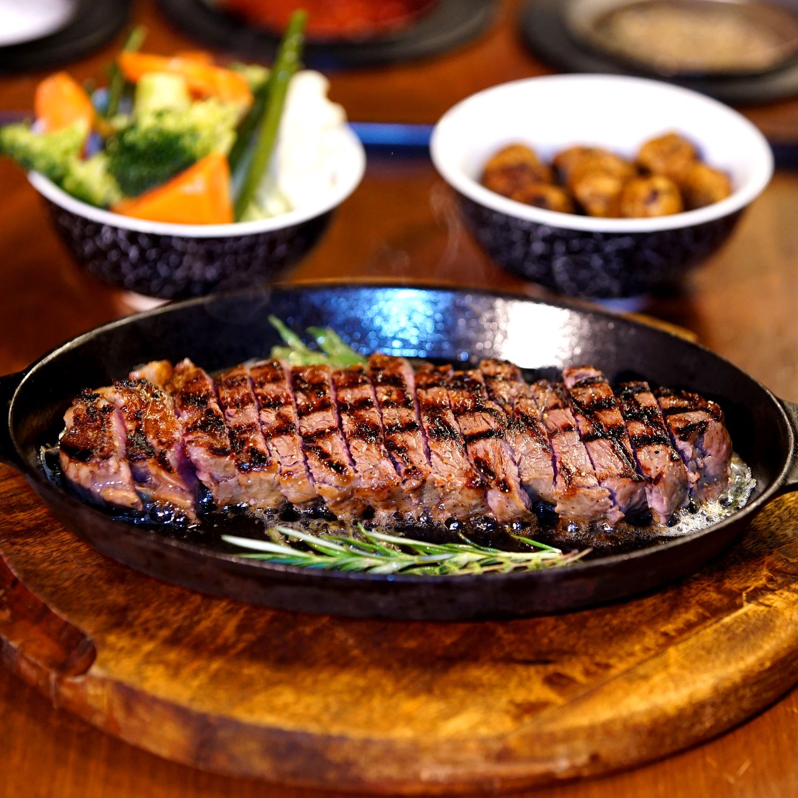 Sliced grilled steak on a cast iron platter with sides