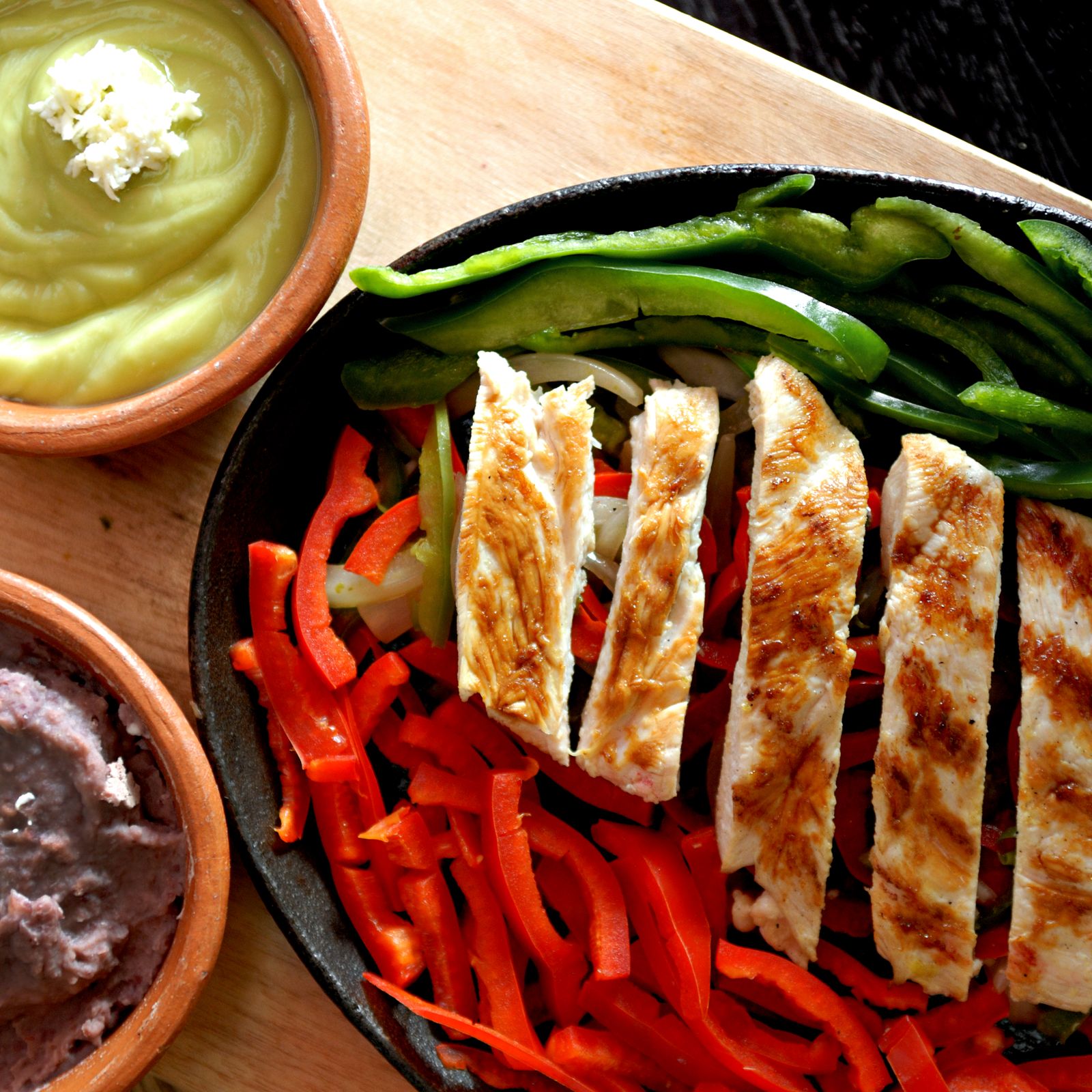 Grilled chicken fajitas with peppers, beans and guacamole