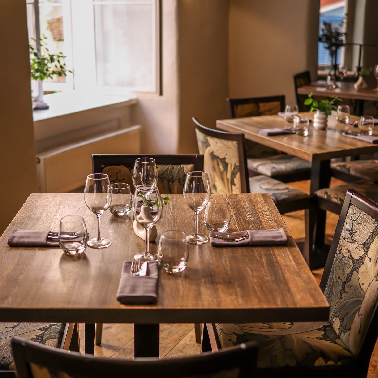 Sol y Sabor dining room with wooden tables set for dinner