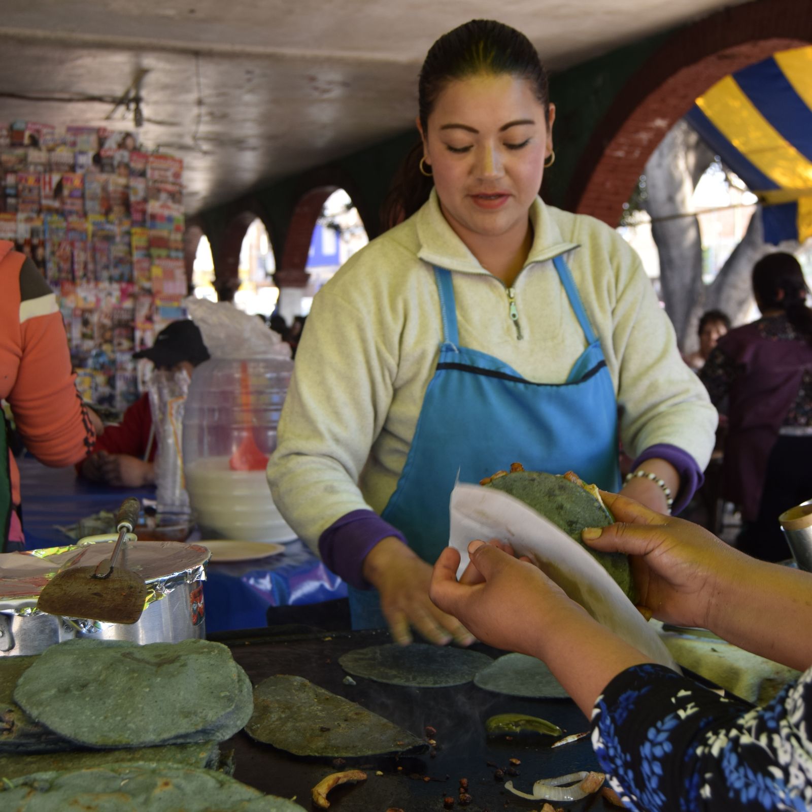 Cooks pressing and griddling fresh masa tortillas by hand
